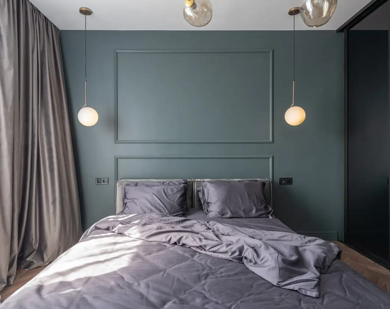 Interior design of modern bedroom with unmade bed under luminous lamps at sunlight