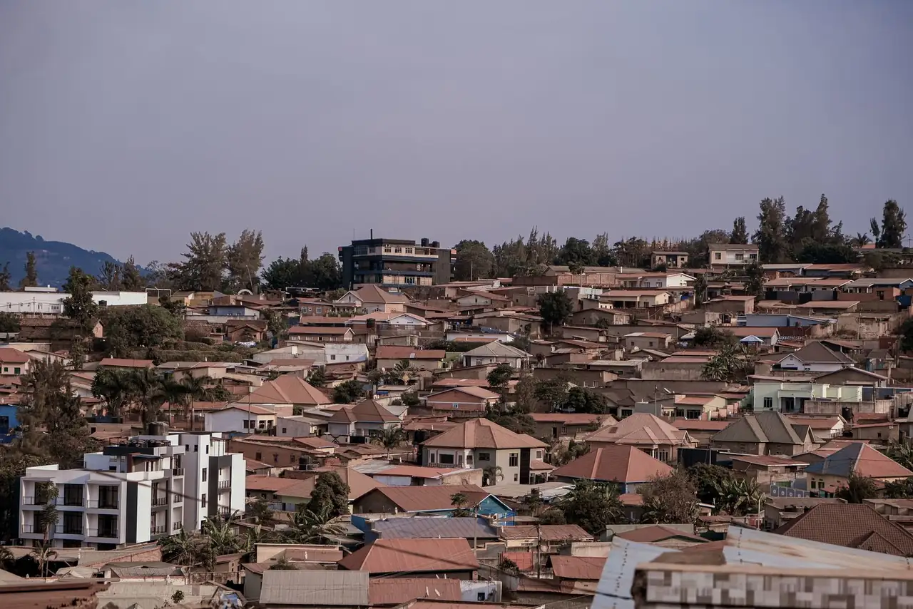 Scenic aerial view of dense urban rooftops against a picturesque hilly backdrop under a clear sky.