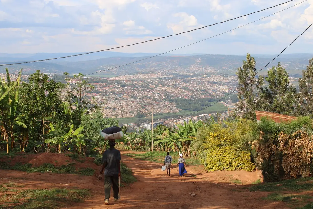A panoramic view of Kigali with people walking on a rural path surrounded by greenery.