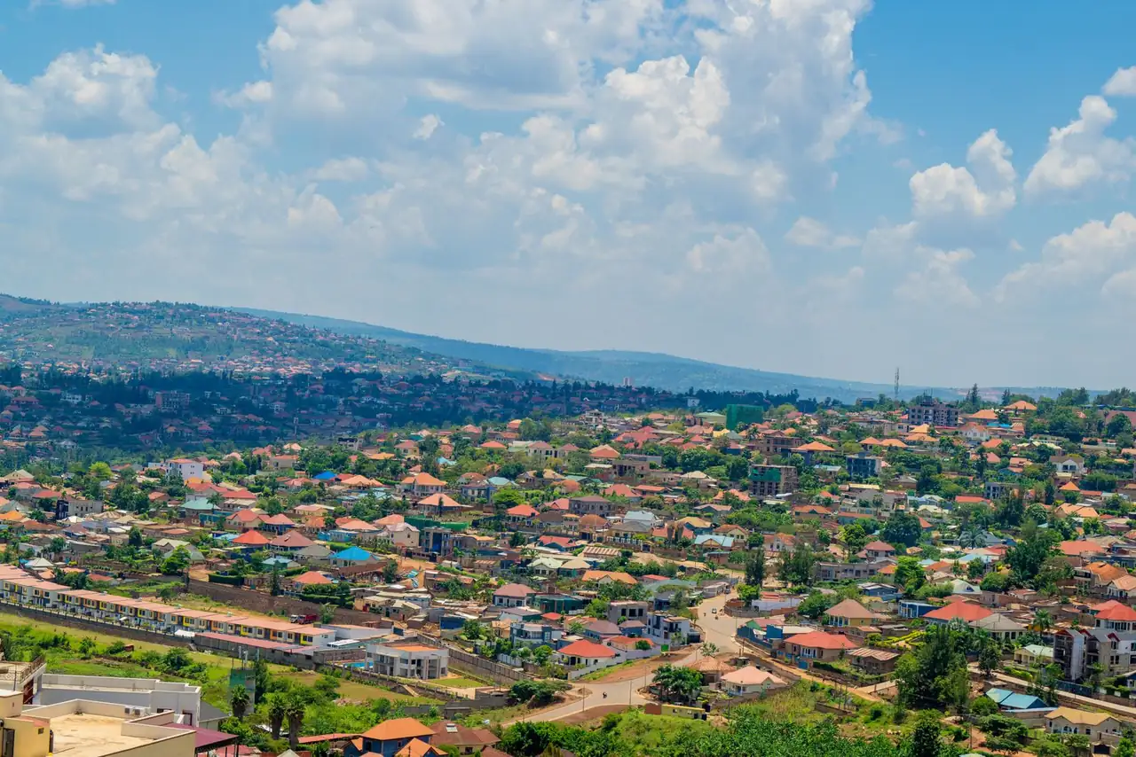 Aerial view of Kigali cityscape with colorful rooftops and vibrant greenery under a bright sky.