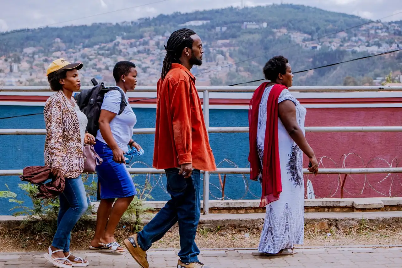 Group of four adults walking on city sidewalk with vibrant background, showcasing cultural diversity.