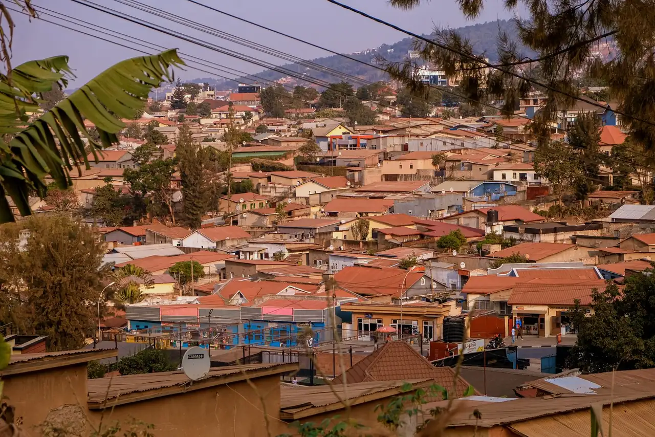 Aerial view of Kigali's suburban rooftops with lush hills in the background, showcasing vibrant community life.